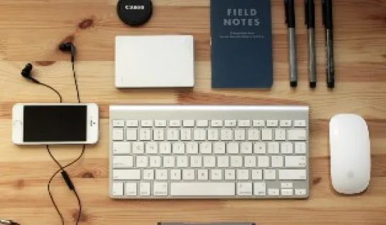 Computer accessories: mouse, keyboard, pens, cell phone, ear phones and note pads