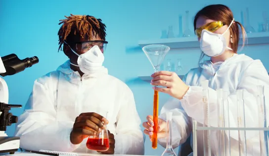 Two students are holding test tubes with different substances in them