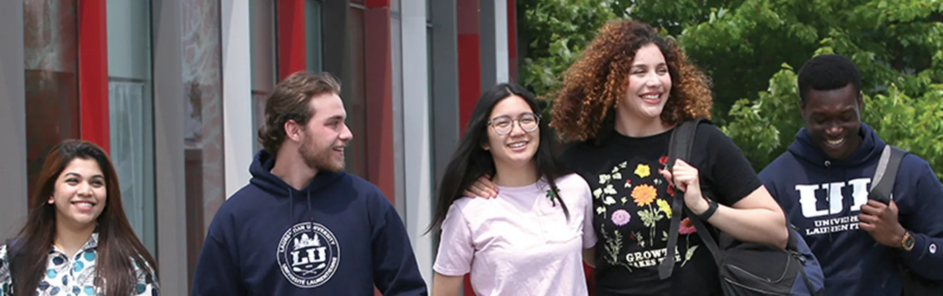 5 étudiants marchant à l'extérieur du centre étudiant
