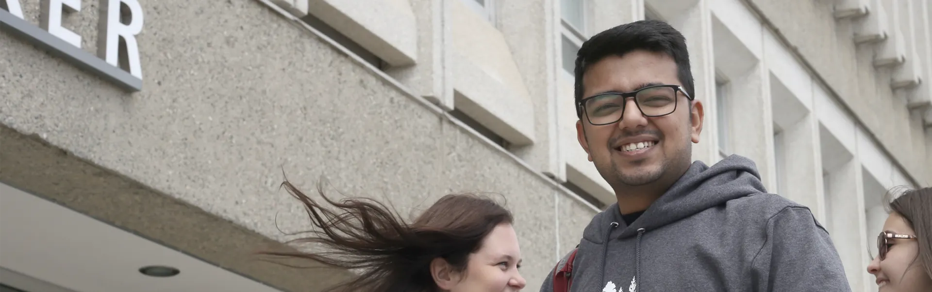 A student smiling at the camera, in front of the Parker Building.
