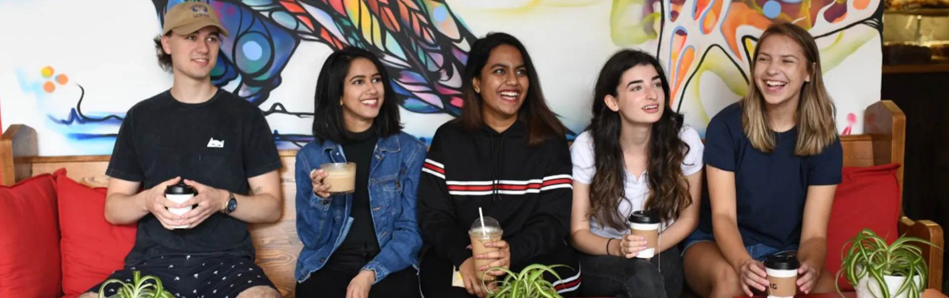 A group of students on a couch with their drinks from a local coffee shop.