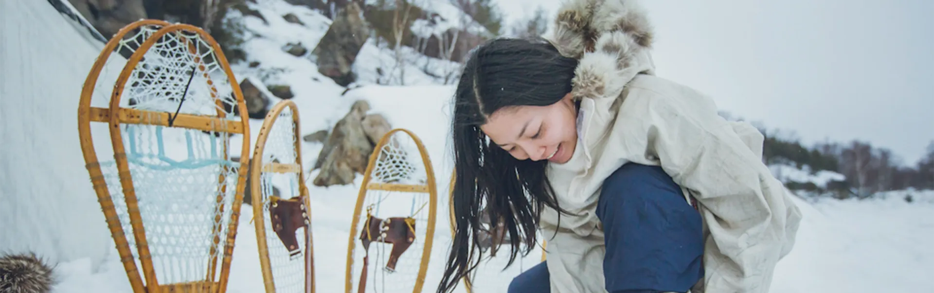 Girl tying up snowshoes in winter