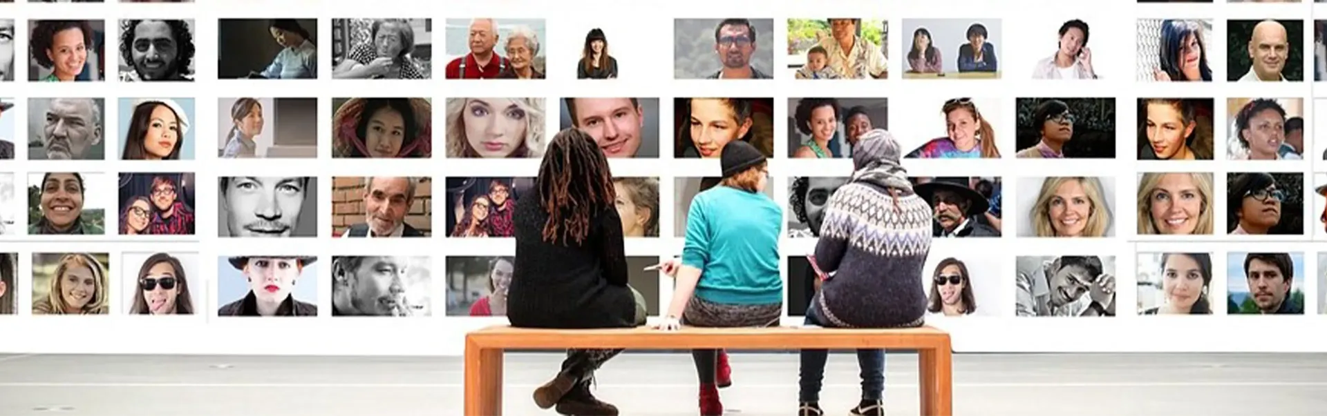 Trois personnes assises sur un banc dans une galerie d'art, regardant les photos affichées au mur.