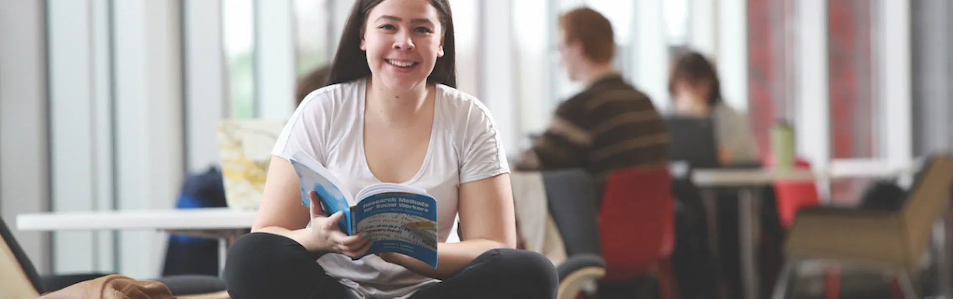 Un étudiant examine un livret d'admission tout en regardant la caméra.