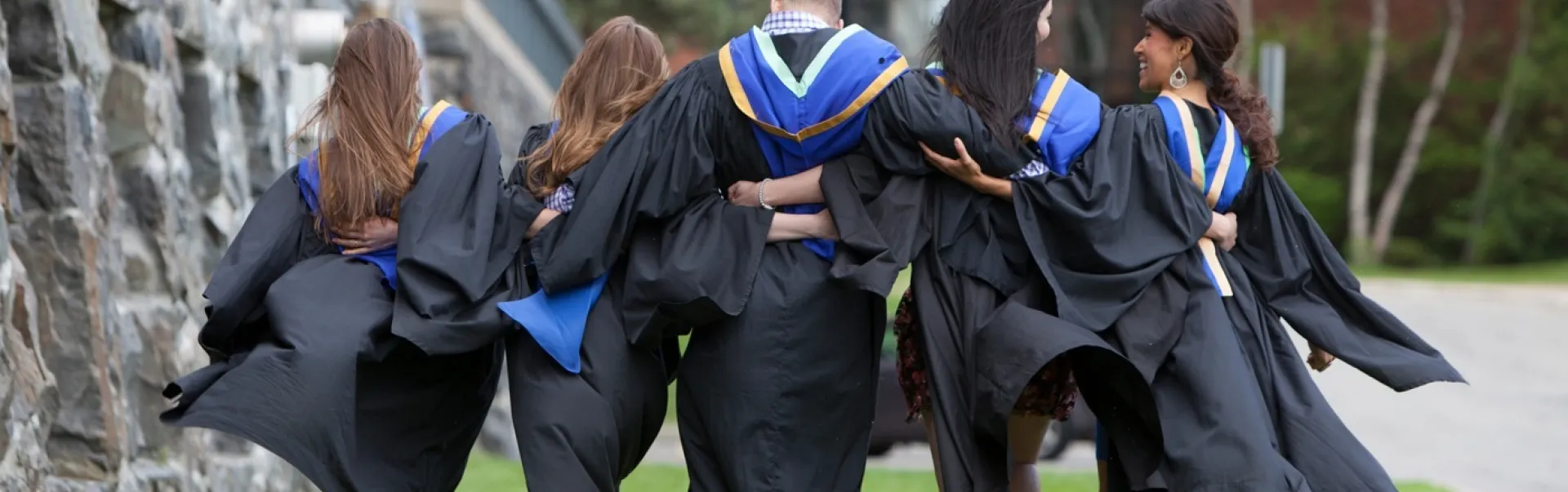 Diplômés marchant ensemble avec leurs bras autour de l'autre