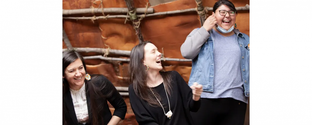 Dr. Joey-Lynn Wabie, Marnie Anderson and Cheyenne Oeschsler laughing together in the wigwam on campus.