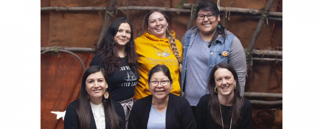 A group of people in the campus wigwam, smiling.