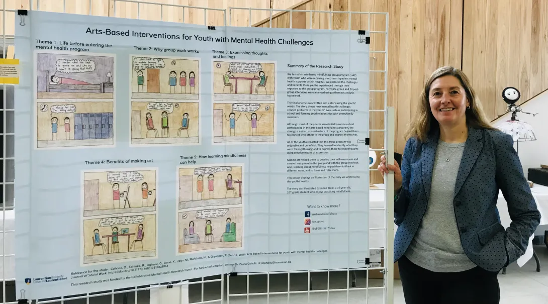 Dr. Diana Coholic standing beside an academic poster about arts-based mental health interventions for youth.