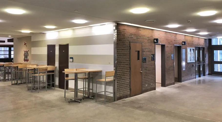 Photo shows the current dated brick wall and access to washrooms, these two imagea show a side-by-side comparison of the Parker Building corridor.