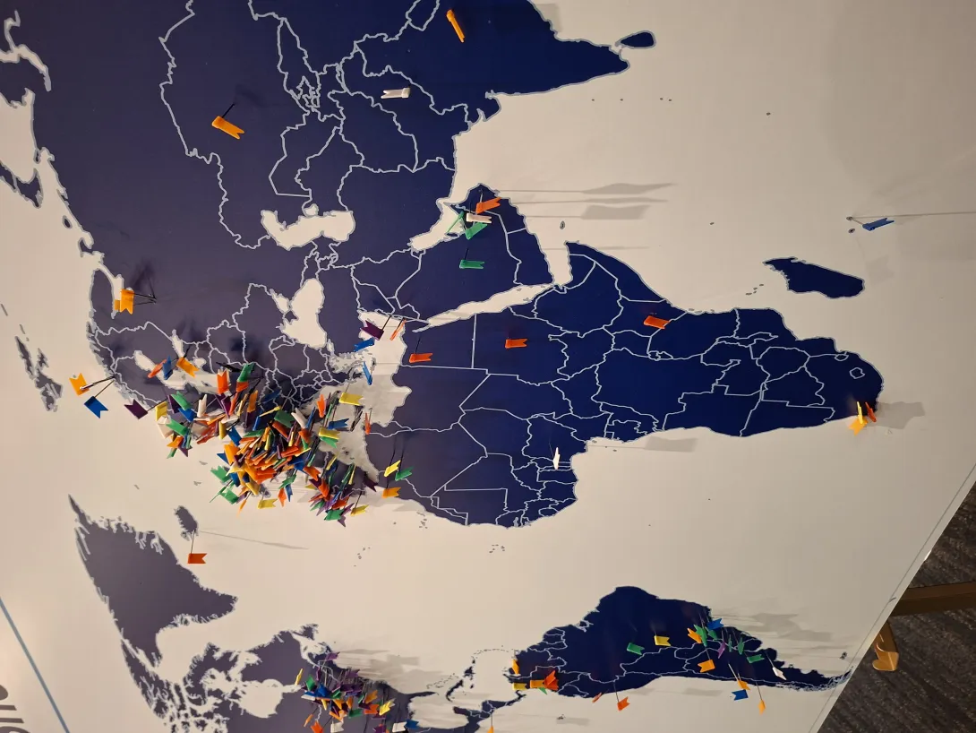 A large interactive world map displayed at the ISFG Congress, densely covered in colorful location pins across Europe, North America, and South America, but showing only a sparse few pins across Africa. The image highlights the significant gap in African representation at global forensic conferences and the importance of bringing research back to underrepresented regions.