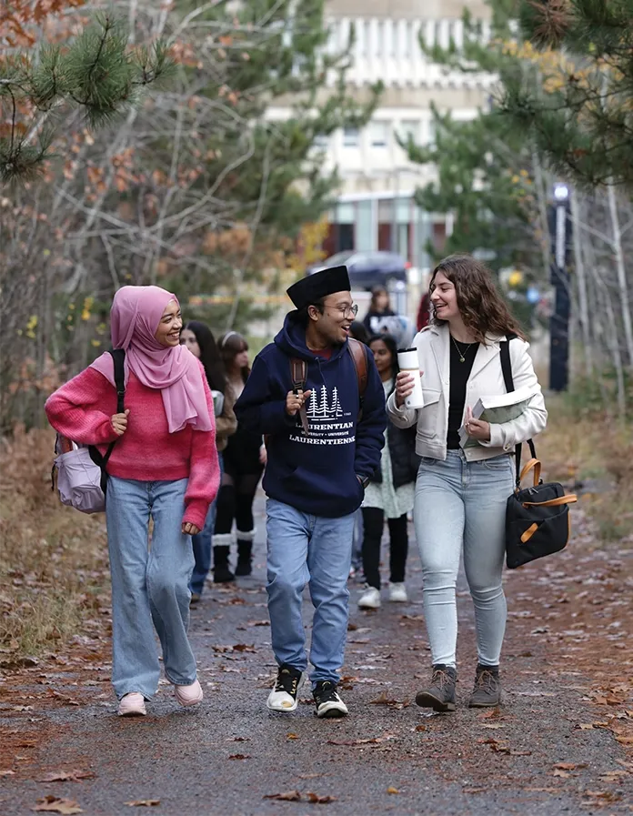 Three students walking on a trail on campus