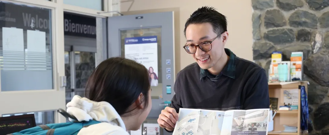 Un étudiant aide un autre étudiant à trouver son chemin sur le campus.
